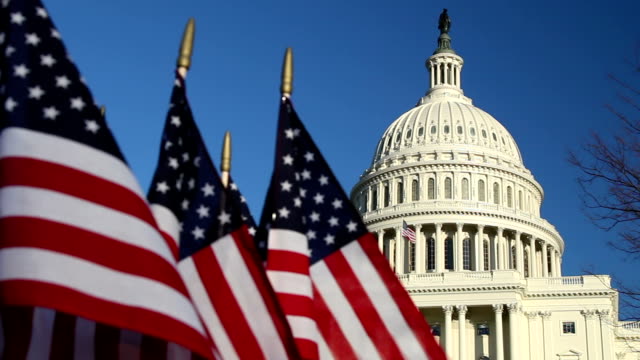 US Capitol dome with American flags in foreground - CU