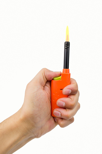 hand pressing the button of orange gas lighter for kitchen with flame