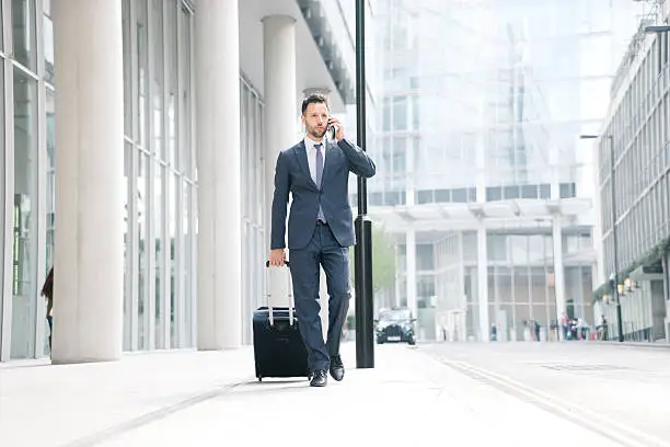 Photo of Businessman On His Cell Phone With Suitcase