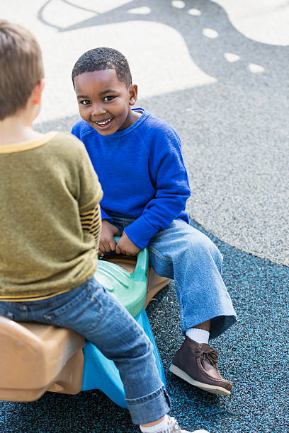 istock Little boy with friend playing on teeter totter 472927142