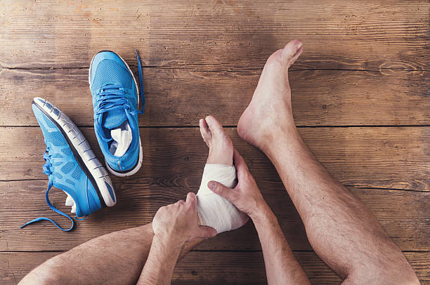 Injured runner Unrecognizable injured runner sitting on a wooden floor background human foot stock pictures, royalty-free photos & images