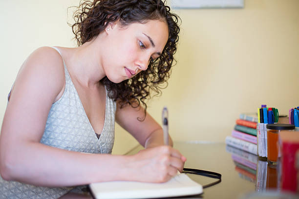 istock Beautiful young woman writing and journaling 472933292