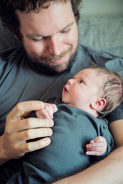 istock Young dad lovingly holding his newborn baby boy. 472938860