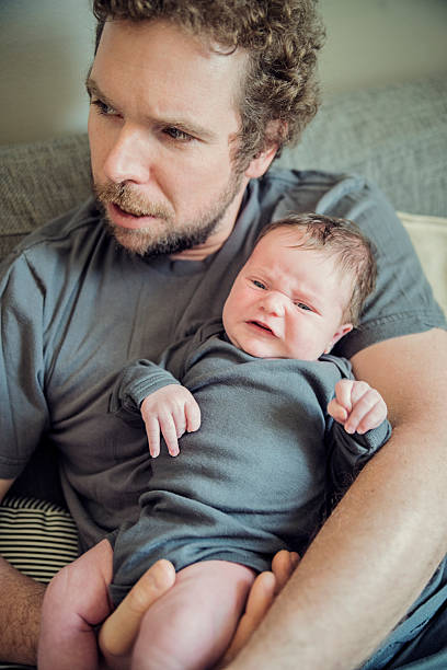 istock Newborn baby is upset, yound dad is looking for help. 472939294