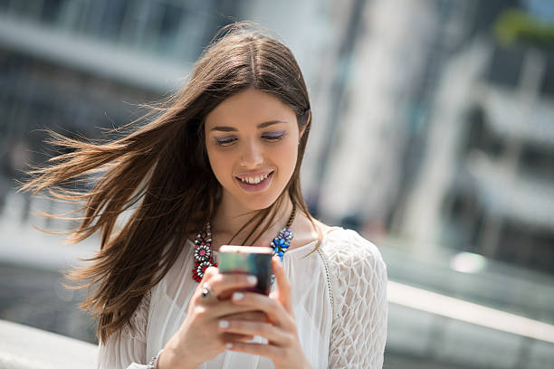 istock Young beautiful woman with white dress using mobile smartphone 472949768