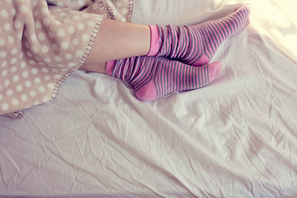istock girl with pink striped socks, sleeping in bed 472952364