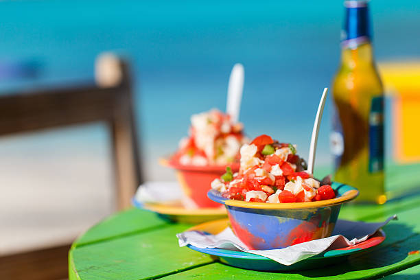 Two Bahamian conch salads on a green table Two bowls of Bahamian conch salad and bottle of beer caribbean culture stock pictures, royalty-free photos & images