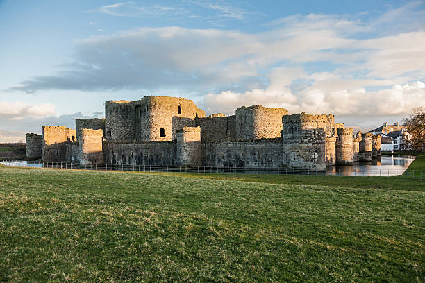 Castle and moat, Beaumaris, Wales - February 21, 2015: Castle and moat, Beaumaris Castle on the Isle of Anglesey. medieval military architecture of the castle is surrounded by the water of the moat. Other buildings can be seen behind the castle  and green field in the foreground  keep fortified tower photos stock pictures, royalty-free photos & images
