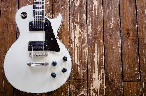 Detroit, MI - May 7, 2015: Vintage Les Paul electric guitar in a white finish with a distressed hardwood floor in the background.