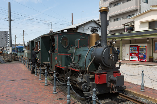 Matsuyama, Japan - April 13, 2015: Train conductors and Botchan Ressha steam locomotive train at the Dogo Onsen Station in Ehime Prefecture, Shikoku, Japan. 