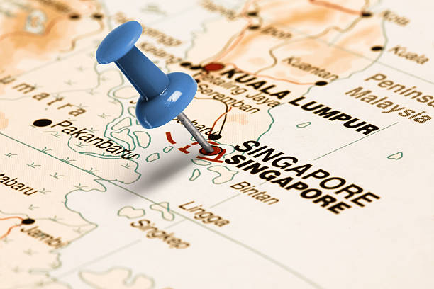 Location Singapore. Blue pin on the map. Series: Travel the world and visit major cities. Blue thumbtack (push pin) that is stuck in a map, which marks the city of Singapore. The map is toned in pastel colors. Concept: Planning travel destinations or journey planning. Close-up view. Studio shot. Landscape orientation. singapore map stock pictures, royalty-free photos & images