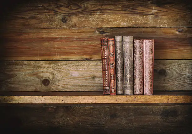 group of antique books on old wooden shelf.