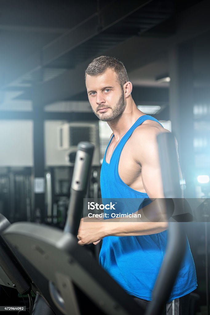 Young man running at treadmill in gym Young adult man running on treadmill in gym 2015 Stock Photo