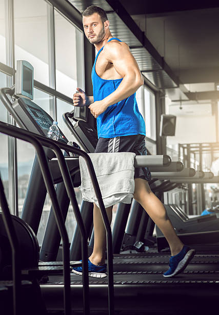istock Young man running at treadmill in gym 472964094