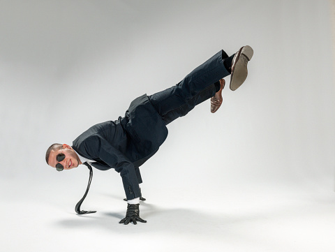 breakdancing businessman performing single handstand looking cool at the camera with sunglasses on, white background. Studioshot