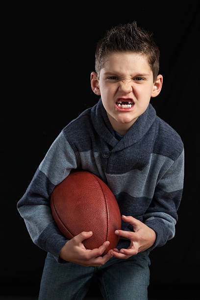 istock Boy Holding Football Missing Teeth 472974550