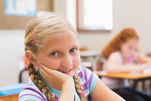 istock Smiling pupil sitting at her desk 472974648
