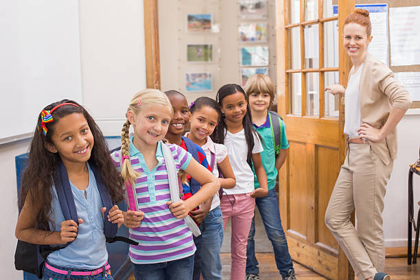 istock Cute pupils smiling at camera in classroom 472977160