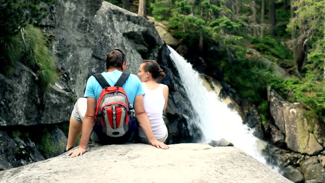 Couple sitting in front of a waterfall