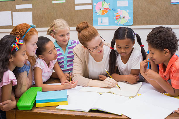 istock Teacher and pupils working at desk together 472977212