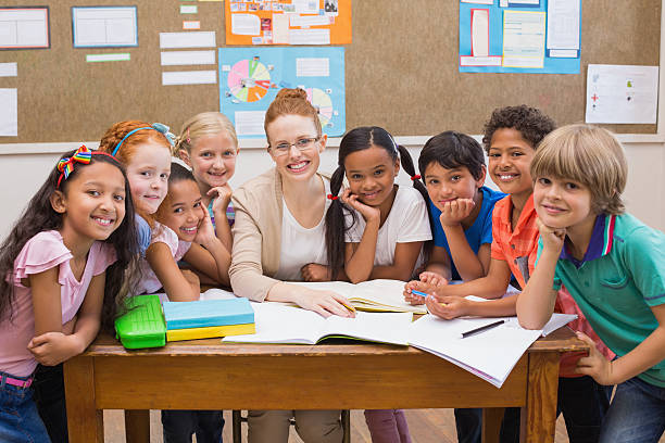istock Teacher and pupils working at desk together 472977218