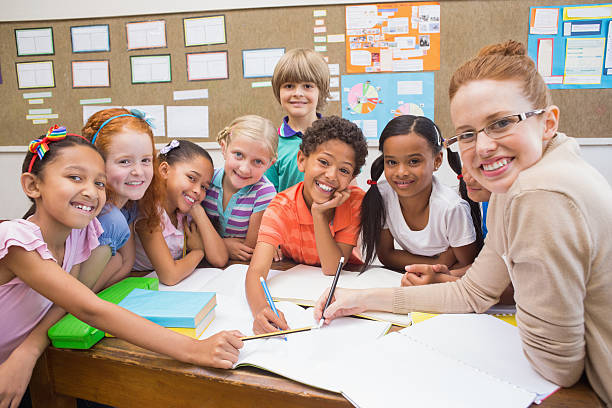 Teacher and pupils working at desk together at the elementary school
