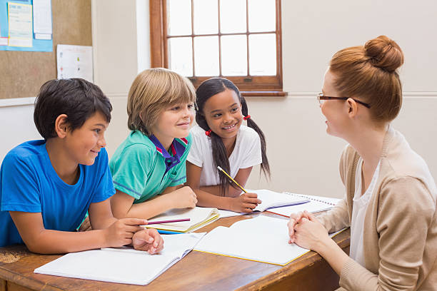 istock Teacher and pupils working at desk together 472977252