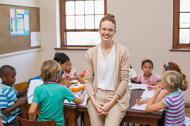 istock Pretty teacher smiling at camera with arms crossed 472977270