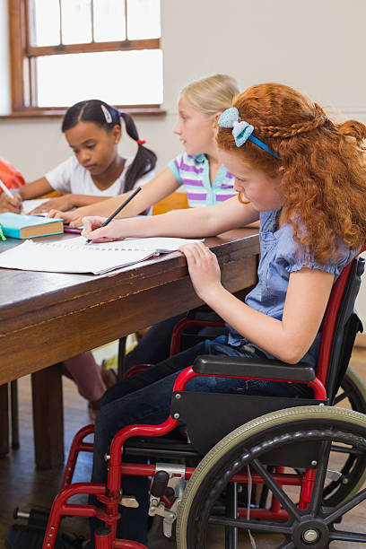 istock Student in wheelchair writing at classroom desk 472977294