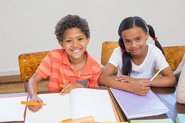 istock Cute pupils smiling at camera in classroom 472977304