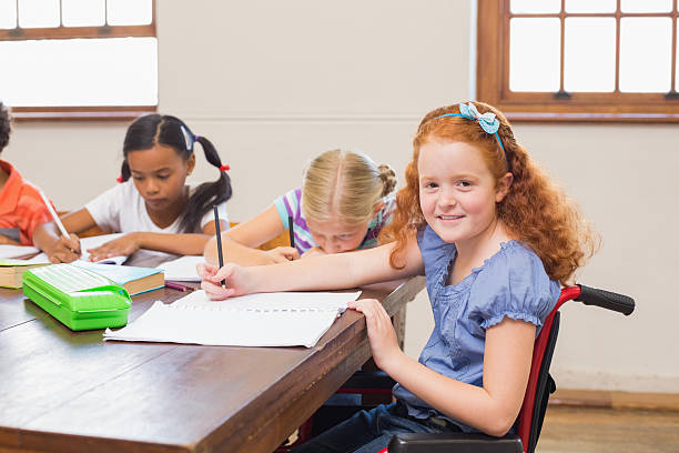 istock Cute pupils writing at desk in classroom 472977312