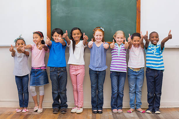 istock Cute pupils smiling at camera in classroom 472977584