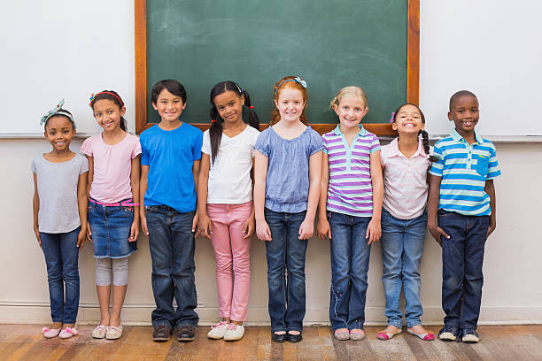 istock Cute pupils smiling at camera in classroom 472977588