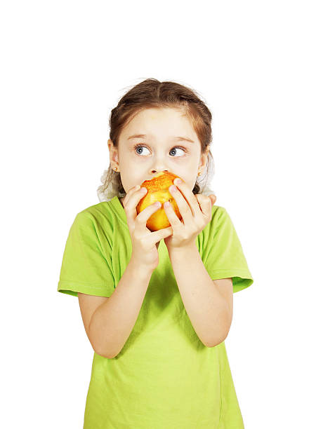 istock Little girl bites a big red apple and looks aside 472984018