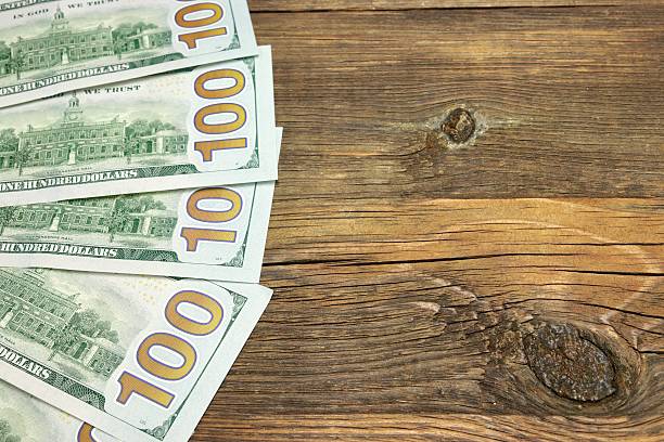 istock Five One Hudred Dollar Bill On The Rough Wood Background 472998202