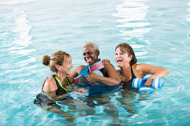Multiracial women in water aerobics class laughing