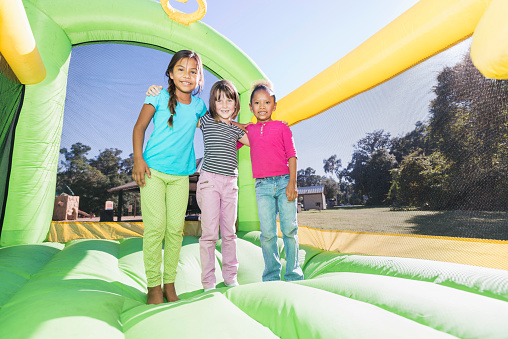 Multi-ethnic girls standing together on bounce house