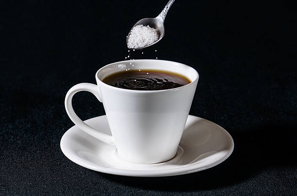 saupoudrer de sucre blanc dans une tasse de café - coffee hot drink cup teaspoon photos et images de collection