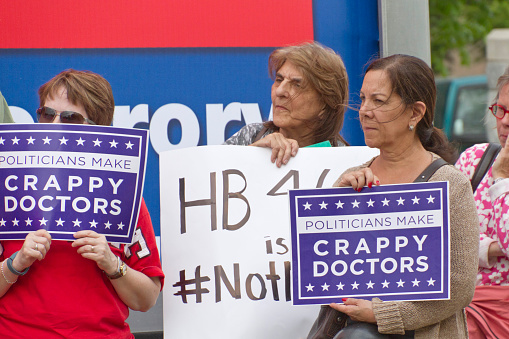 Asheville, North Carolina, USA - May 4, 2015:  Older women hold signs saying politicians make crappy doctors to protest North Carolina's abortion Bill #465 which increases restrictions for women seeking abortions, May 4, 2015 in downtown Asheville, NC
