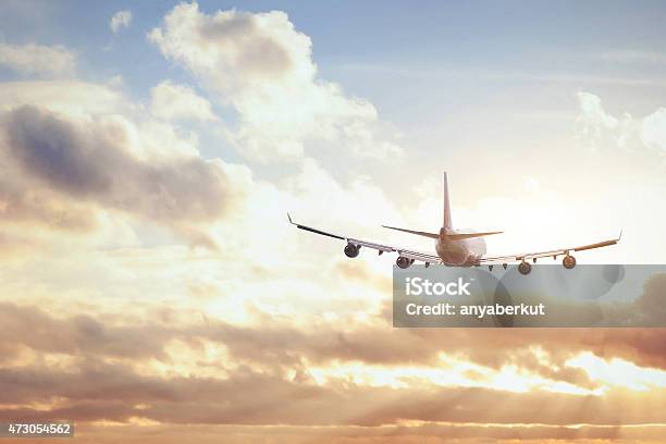 Flying Airplane In The Sky Below Clouds On A Sunny Day Stock Photo - Download Image Now