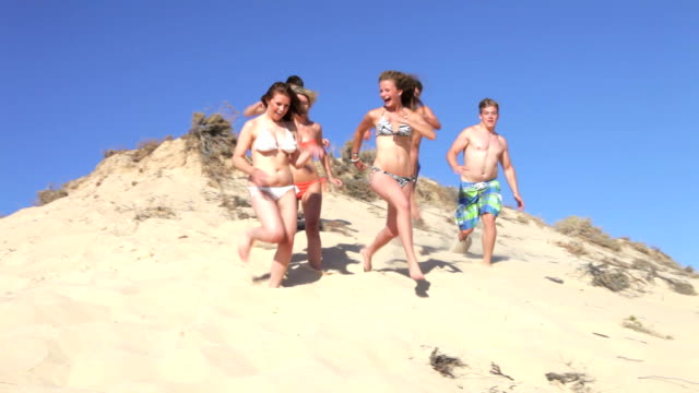 Group Of Teenagers Running Down Sand Dunes