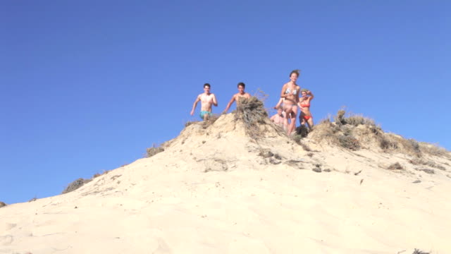 Group Of Teenagers Running Down Sand Dunes