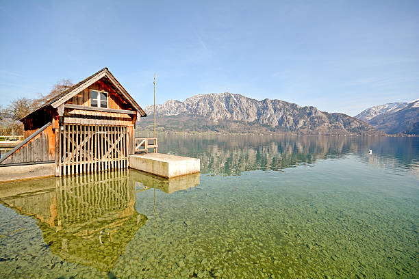 Silent morning in Traunkirchen. Wooden boat on a lake. Mountains in clouds on the background.