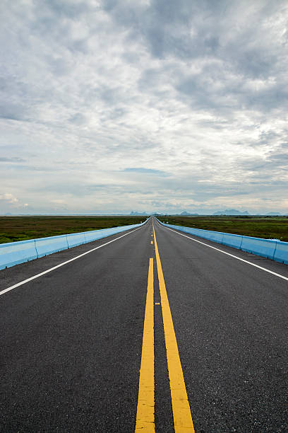 istock Empty road and the yellow traffic lines with clouds. 473068116