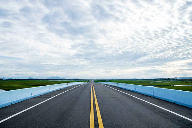 istock Empty road and the yellow traffic lines with clouds. 473070508