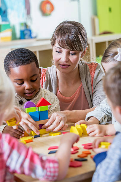 istock Kindergarten teacher helping boy with wooden blocks 473071428