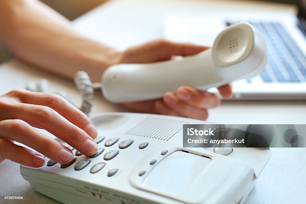A woman using a landline phone calling by phone in the office, hands pressing buttons Telephone Stock Photo