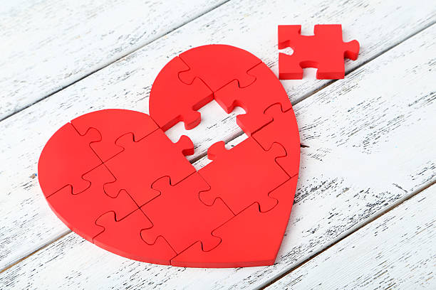 istock Red puzzle heart on white wooden background 473078236