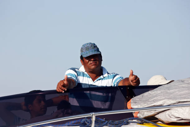 Paracas, Peru - January 20, 2015: Captain and crew on motor boat out at sea off the Pacific coast of the Peruvian fishing village of Paracas. Crew member wearing a baseball cap gives a thumbs up sign