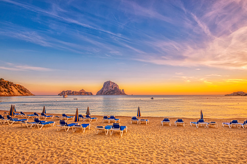 Beautiful beach, boats and Es Vedrà - a small, uninhabited rock island - in the bay of Cala D'hort, Ibiza (Spain) at sunset. 